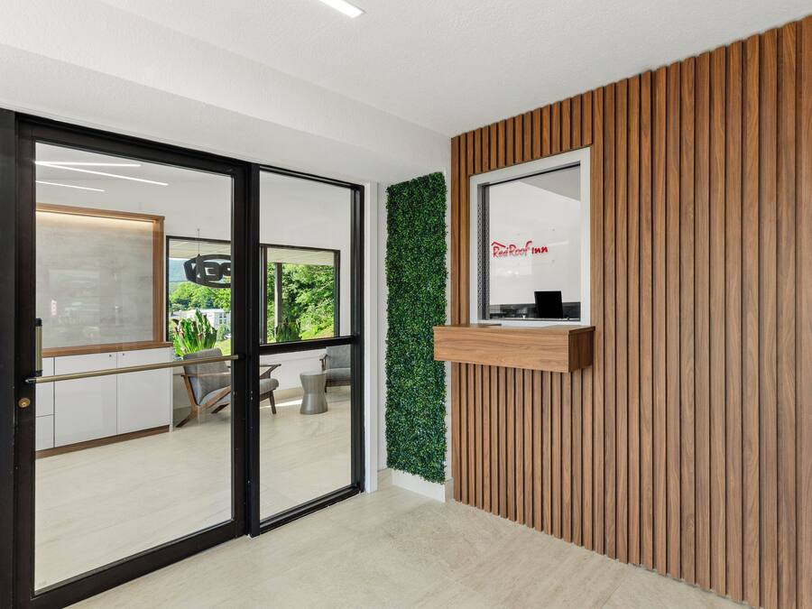 A modern reception area with a wooden panel wall, a green vertical garden, and a reception desk.
