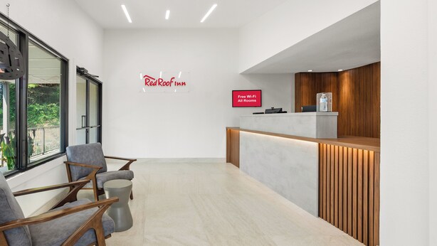 A Red Roof Inn reception area with a modern design, including a reception desk, seating area, and a wall-mounted sign indicating free Wi-Fi availability. - Red Roof Inn Wytheville (Wytheville)