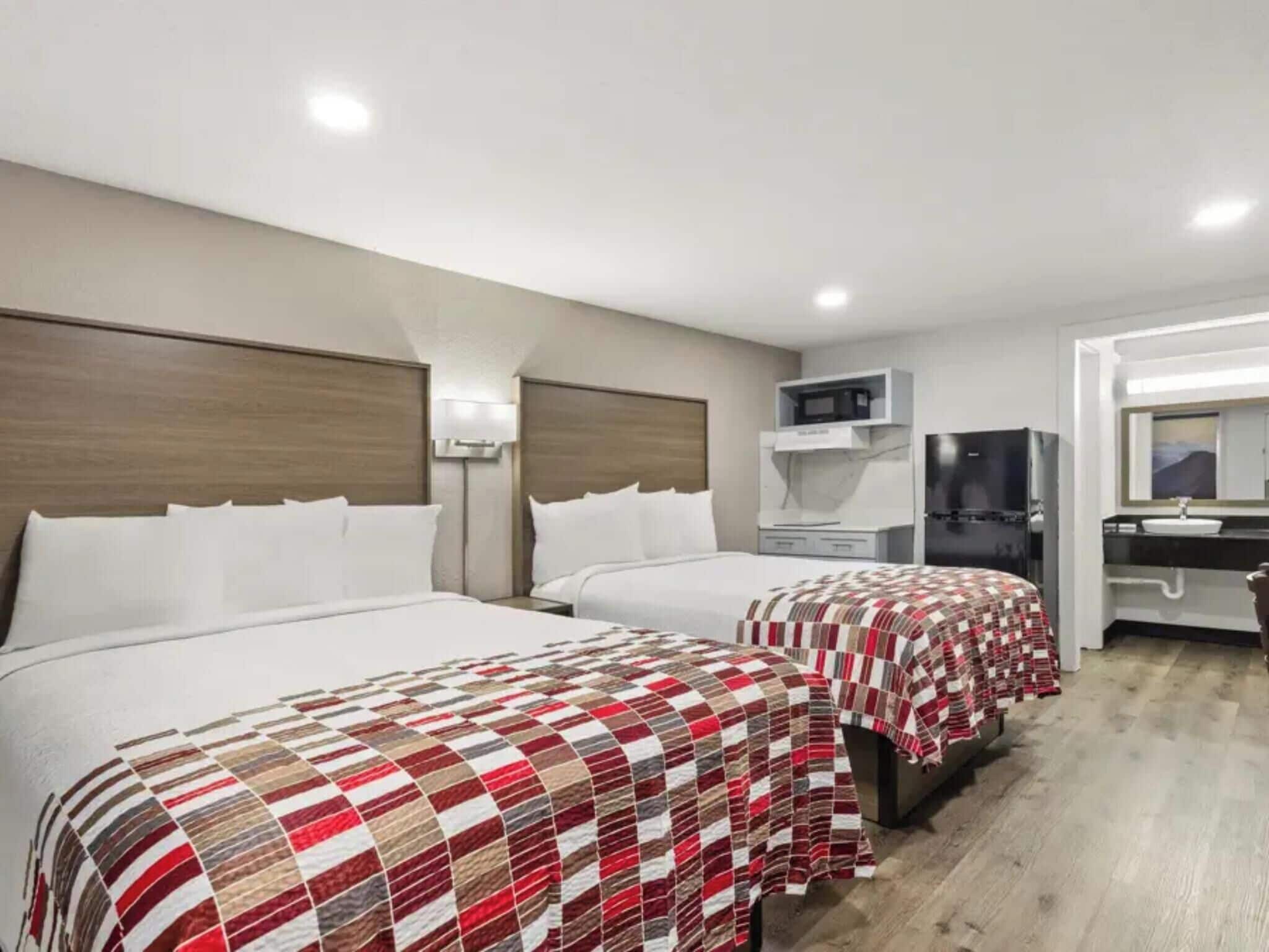 Une chambre d’hôtel avec deux lits, un four à micro-ondes, un réfrigérateur, un évier et un miroir.