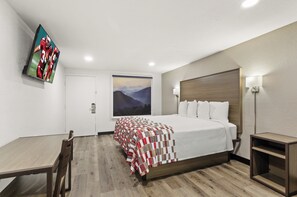 A hotel room with a bed, a desk, a chair, a TV mounted on the wall, and a painting on the wall. - Red Roof Inn Wytheville (Wytheville)