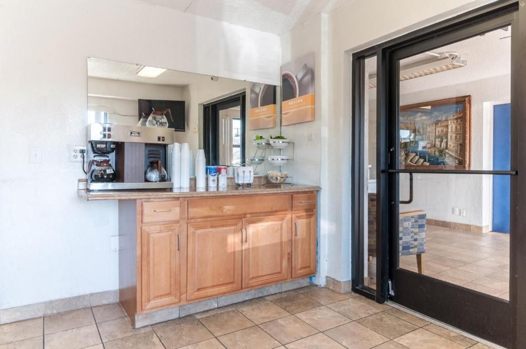 A kitchen with wooden cabinets, a coffee machine, and a tiled floor.