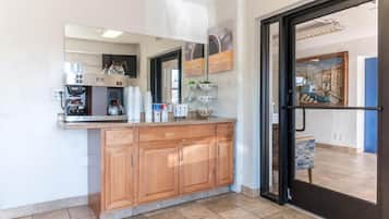 A kitchen with wooden cabinets, a coffee machine, and a tiled floor.