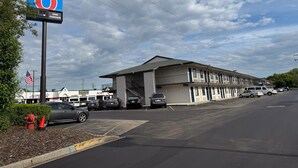 Ein Motel mit großer Schautafel, Parkplatz und einem Gebäude mit vielen Fenstern und überdachter Zufahrt.