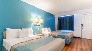 Ein Hotelzimmer mit zwei Betten, einem Nachttisch, einem Telefon und einem Fenster mit Vorhängen.