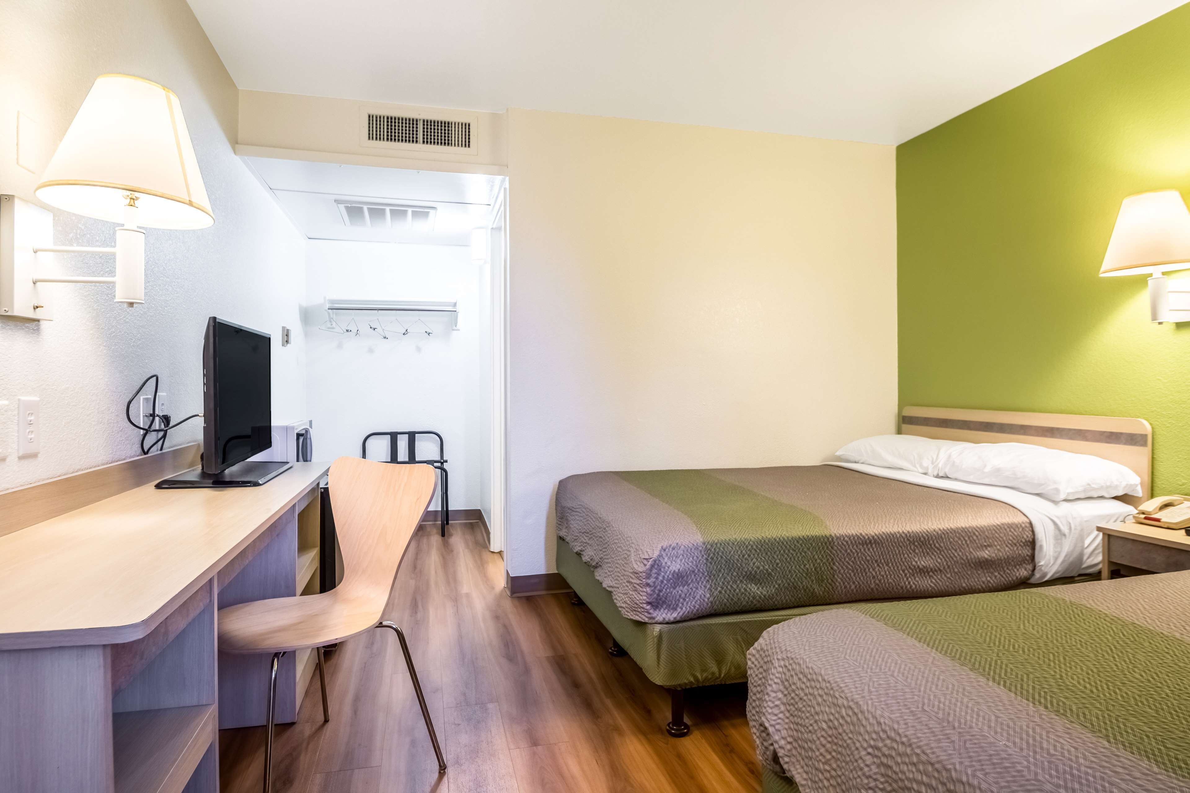 Una habitación de hotel con escritorio, silla, dos camas y televisor.