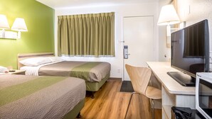 A hotel room with two beds, a desk with a TV, and a chair. - Motel 6 Pueblo, CO - I-25 (Pueblo)