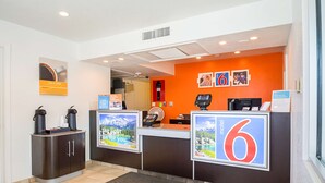 A hotel reception area with a modern design, featuring a reception desk, a coffee station, and a large number '6' sign indicating the hotel name. - Motel 6 Pueblo, CO - I-25 (Pueblo)