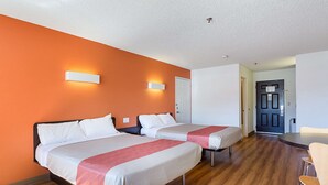 A hotel room with two beds, a dining table, and a door leading to the hallway. - Motel 6 Williams, AZ - West - Grand Canyon (Williams)