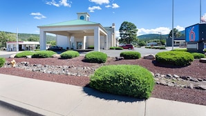A gas station with a green roof, surrounded by landscaped bushes and rocks. - Motel 6 Williams, AZ - West - Grand Canyon (Williams)