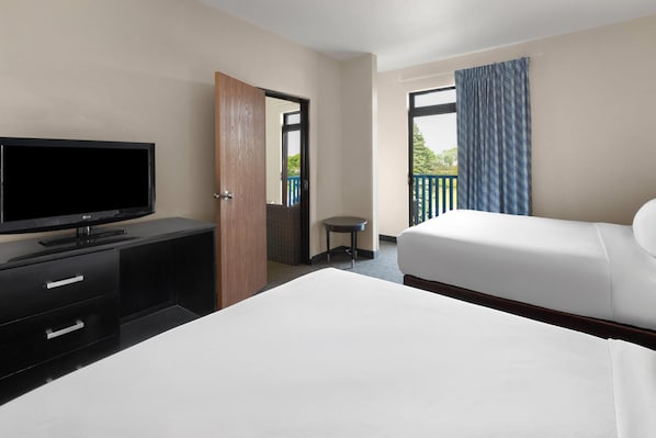 Habitación de hotel con cama, televisor en una cómoda, una mesita y un balcón con vistas.