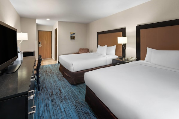 A hotel room with two beds, a desk with a TV, and a blue carpet. - Days Inn by Wyndham Mackinaw City/Bridgeview Area (Mackinaw City)