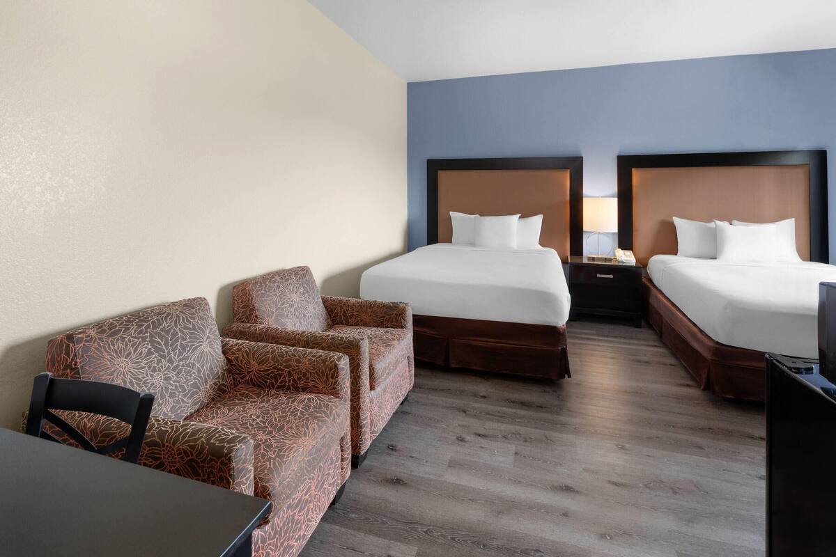 Habitación de hotel con dos camas, un sofá, una mesa y un televisor.