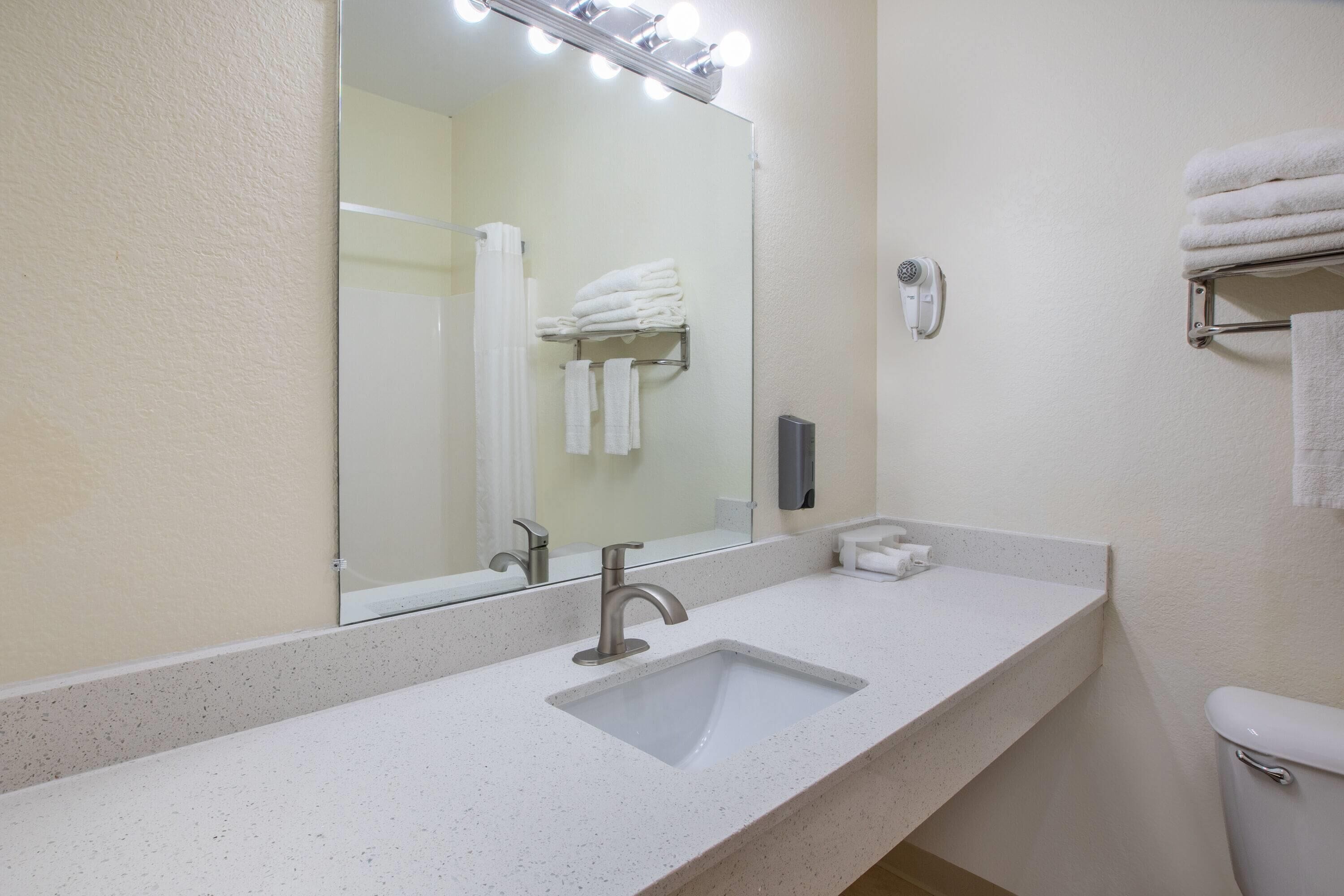 A bathroom with a sink, mirror, and towel rack.