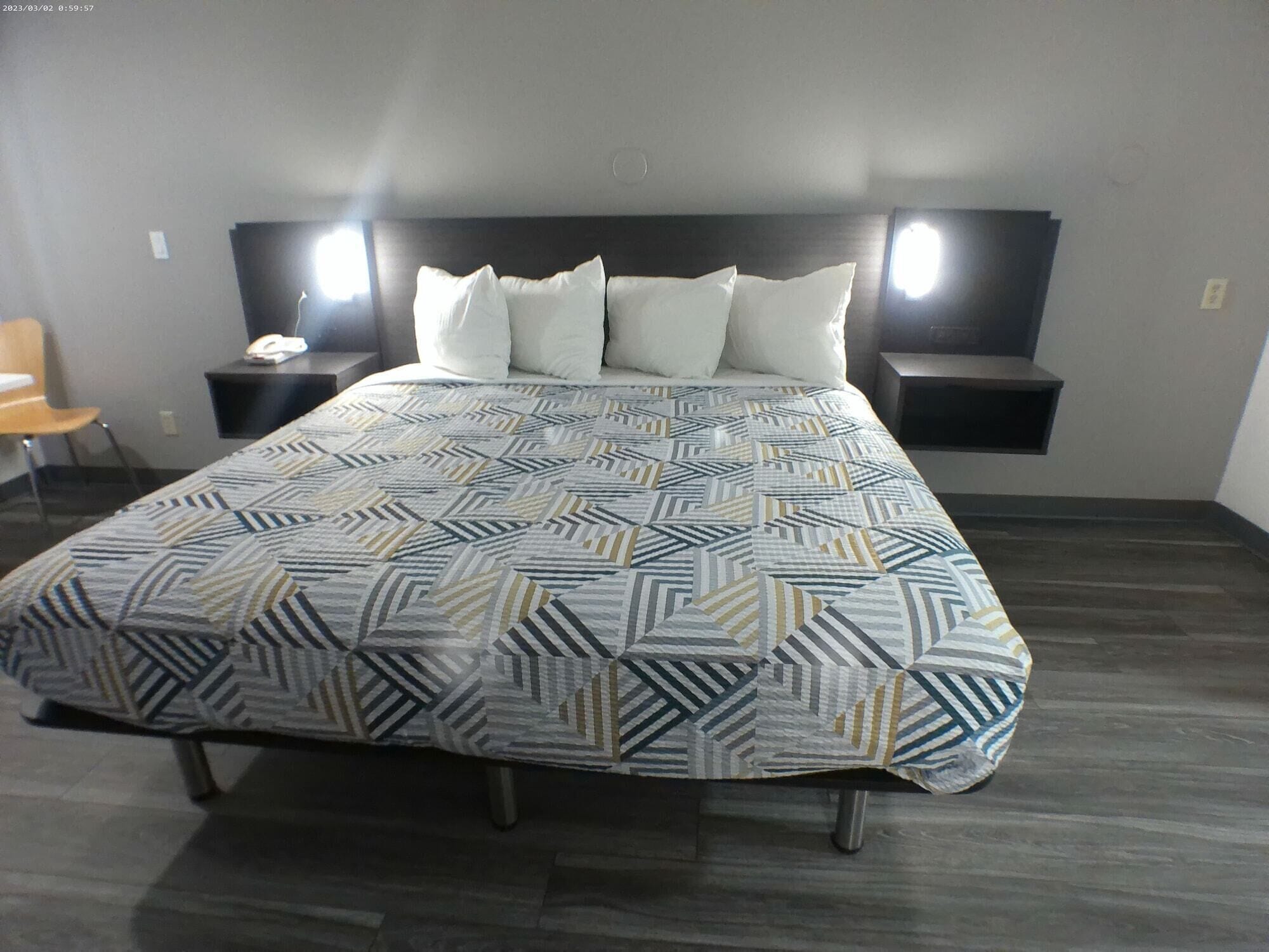 Habitación de hotel con una cama grande, dos mesitas de noche, una silla y una mesita auxiliar.