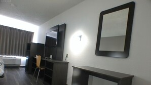 A hotel room with a desk, chair, and a large mirror on the wall. - Motel 6 Winslow, AZ (Winslow)