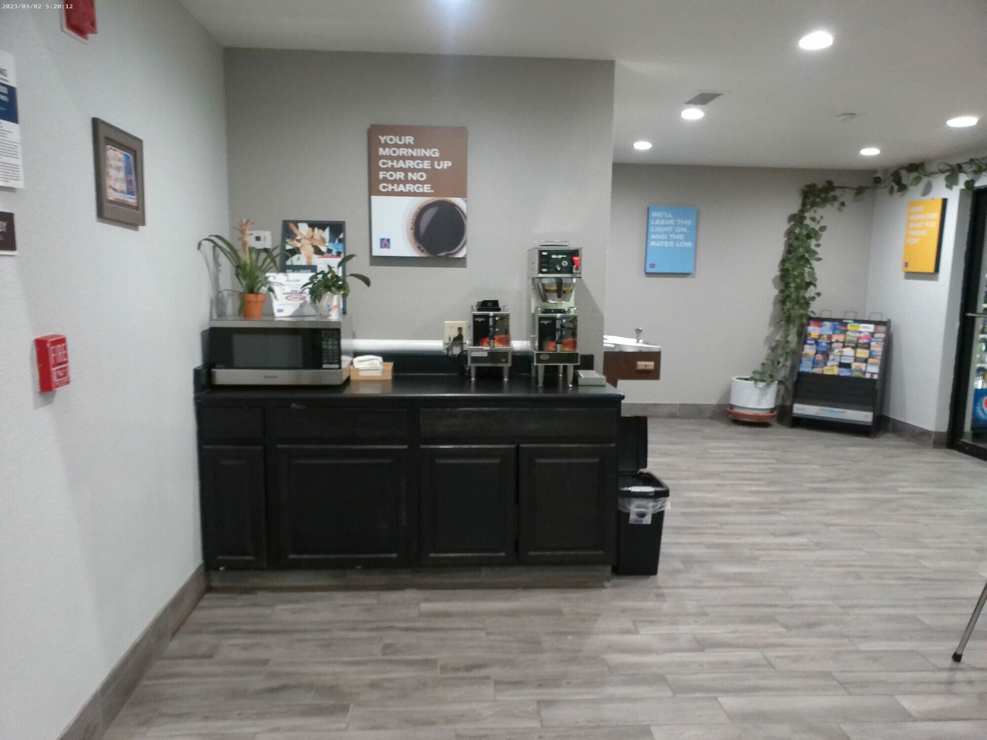 A reception area with a counter, coffee machines, and a sign about morning charge.