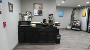 A reception area with a counter, coffee machines, and a sign about morning charge.