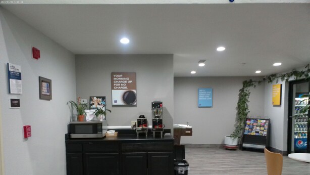 A reception area with a counter, a coffee machine, a microwave, a trash bin, and a chair. - Motel 6 Winslow, AZ (Winslow)