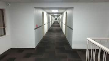 A long, narrow hallway with white walls and a checkered carpet.