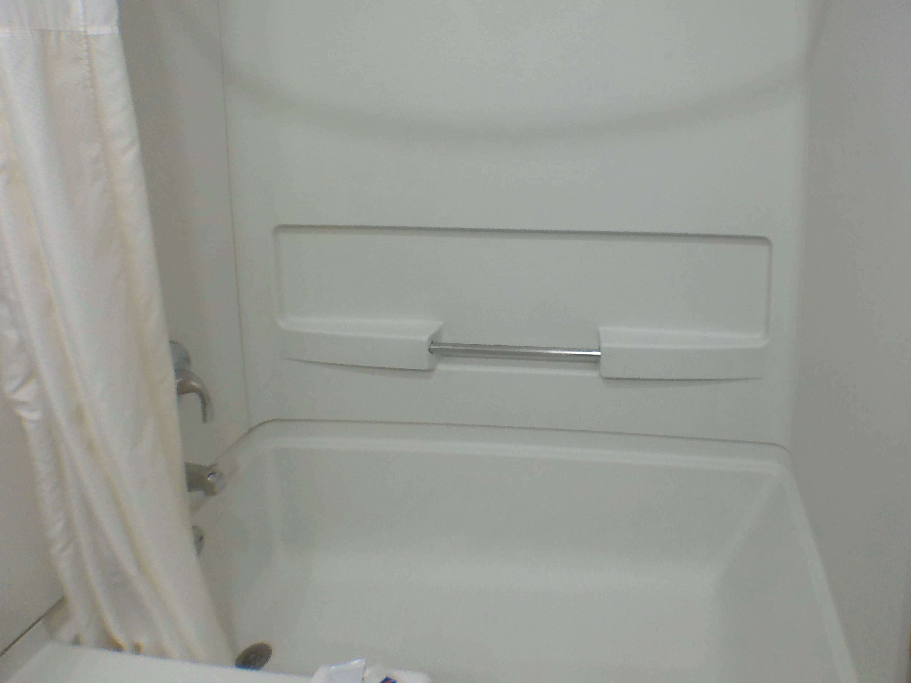 Una bañera blanca con cortina de ducha y un perchero para toallas.