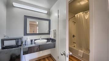 A bathroom with a sink, mirror, and shower.