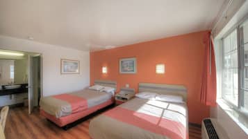 Habitación de hotel con dos camas, baño y ventana con cortinas.
