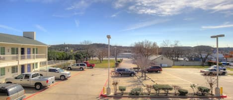 A parking lot with several cars, a building with a balcony, and a clear sky.