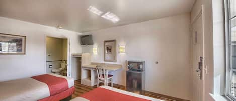 Habitación de hotel con dos camas, un escritorio, una silla, un televisor y una ventana.
