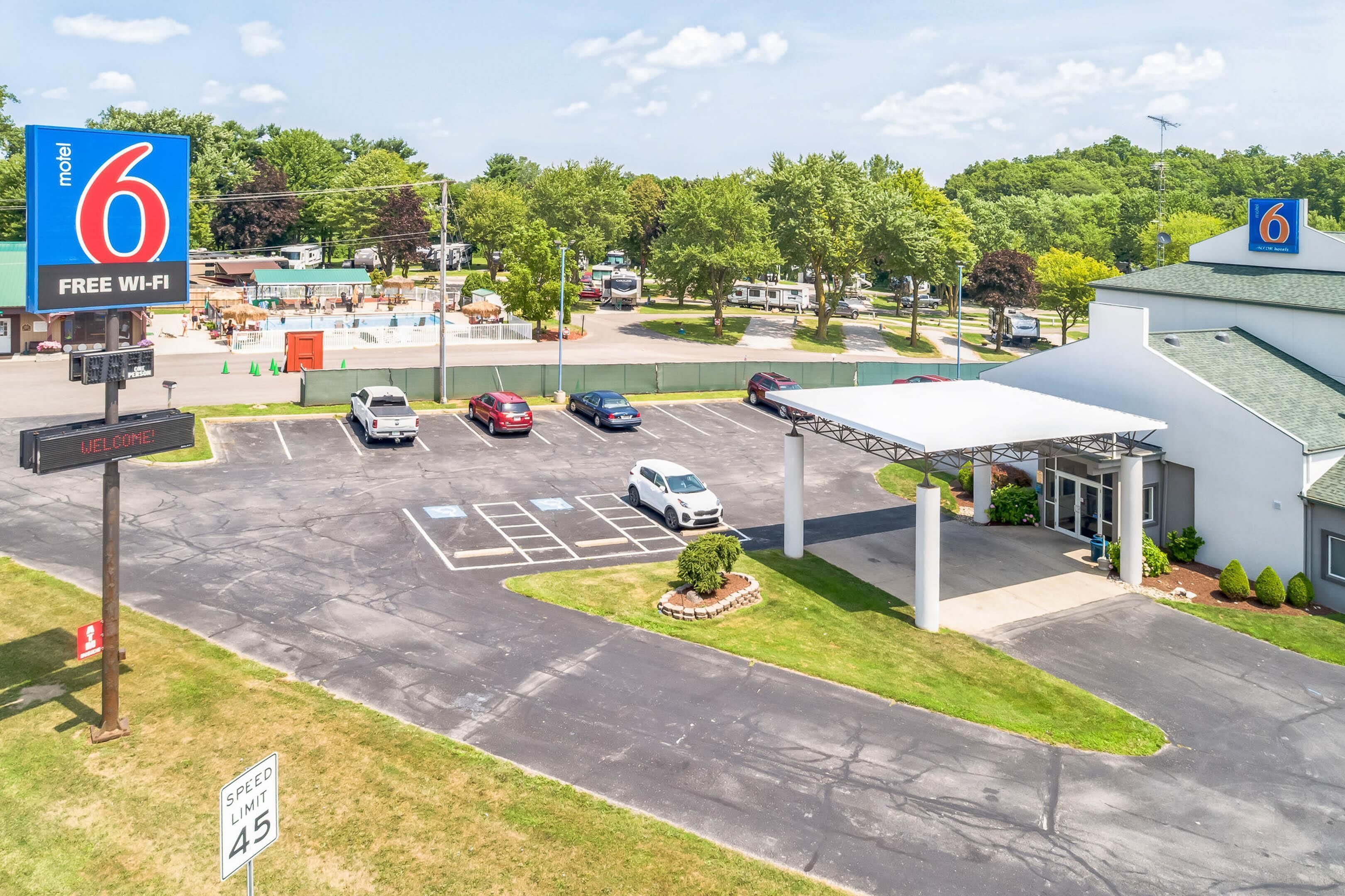 A motel with a large sign, a parking lot, and a covered area.