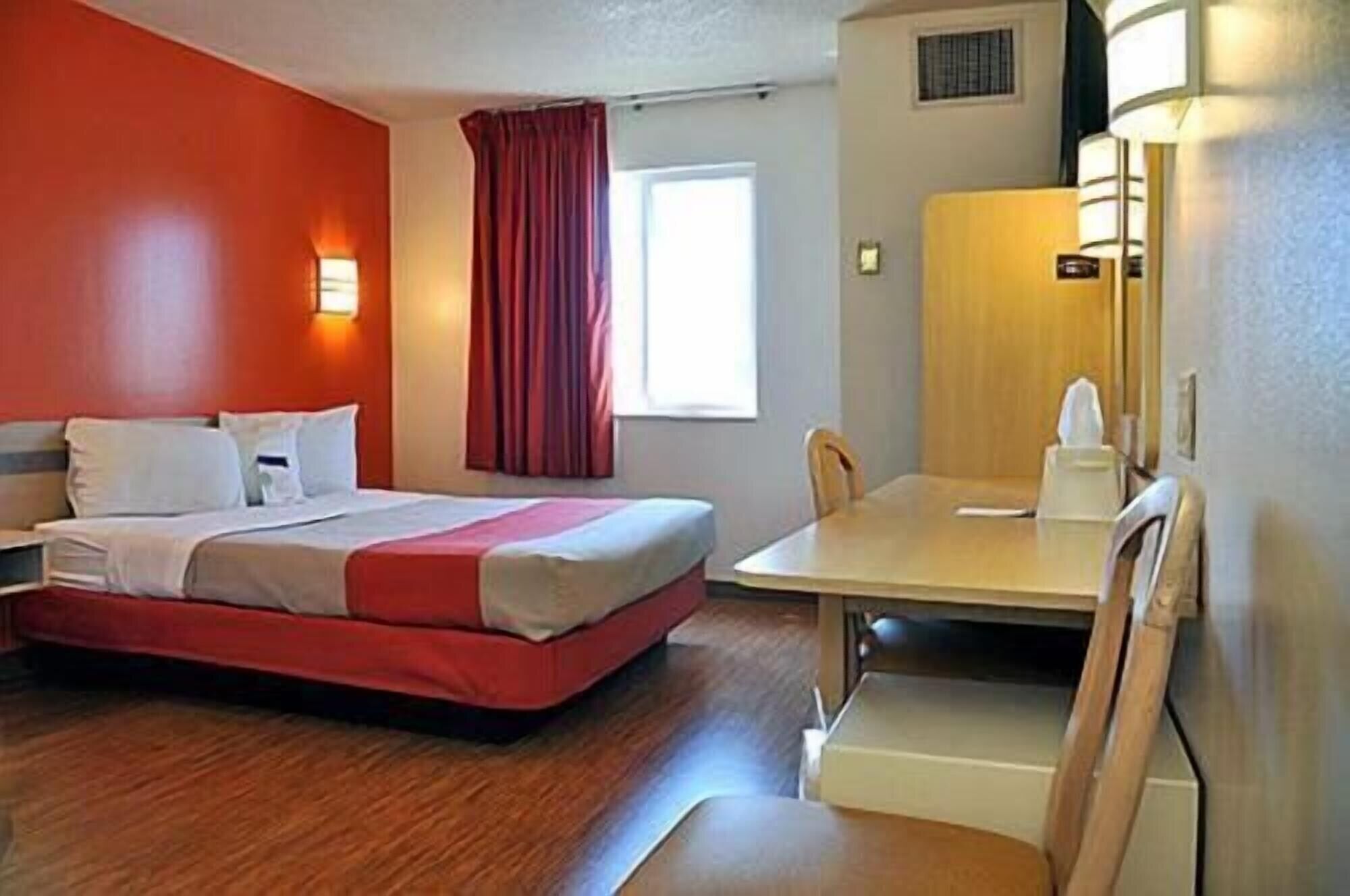 A hotel room with a bed, a desk, and a chair.