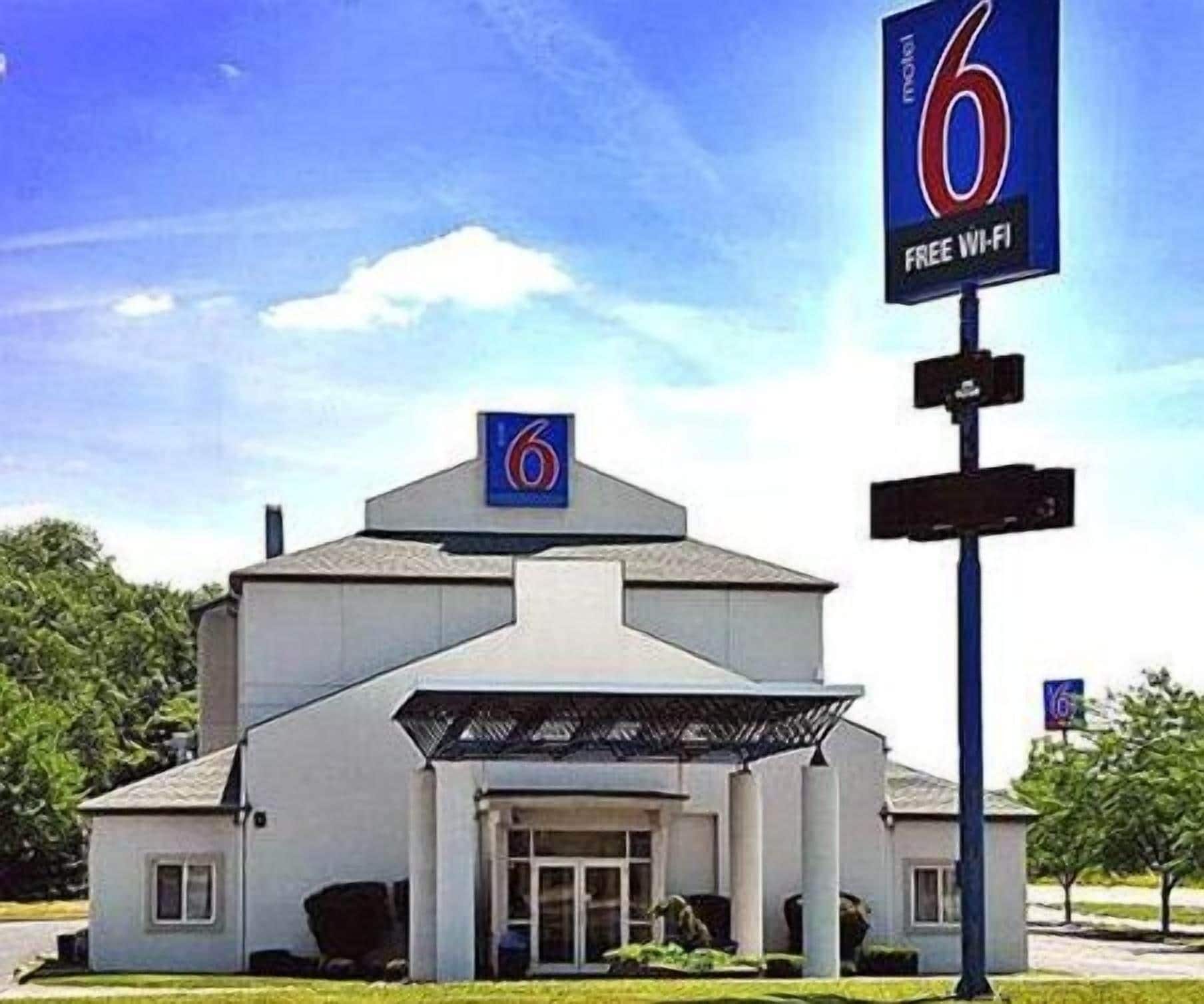 Un motel avec un grand panneau indiquant le chiffre « 6 », un panneau indiquant « WI-FI GRATUIT » et une entrée abritée.