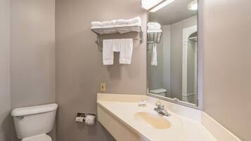Ein Badezimmer mit Toilette, Waschbecken, Spiegel, Handtuchhalter und Toilettenpapierhalter.