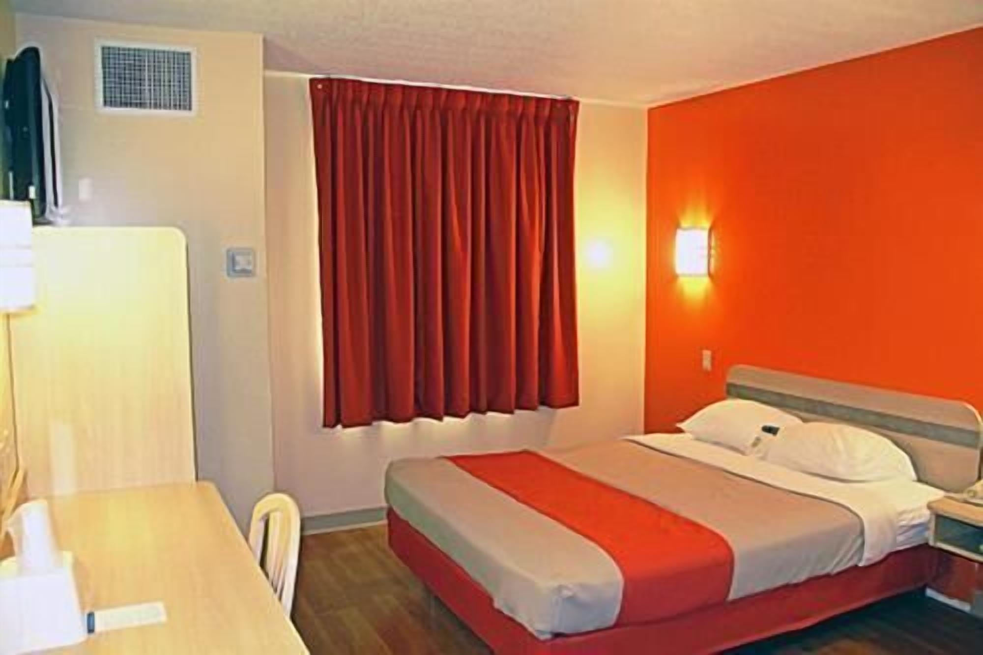 A hotel room with a bed, a desk, and a chair.