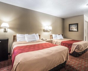 A hotel room with two beds, a desk, a lamp, and a framed picture on the wall. - Rodeway Inn Hurricane - Zion National Park Area (Hurricane)