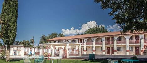 A hotel with a courtyard, outdoor seating, and a large tree.