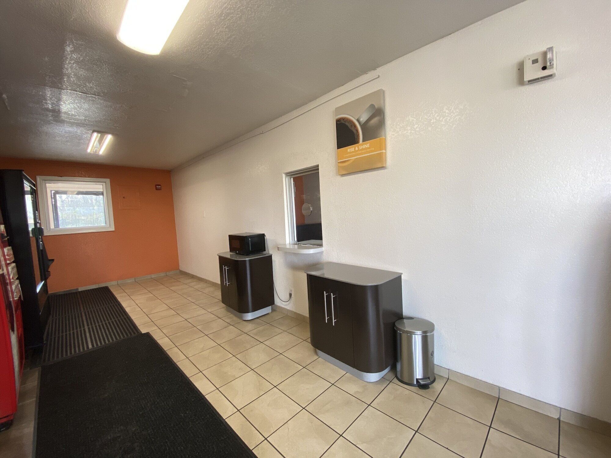 A kitchen with a microwave, a trash can, and a cabinet.