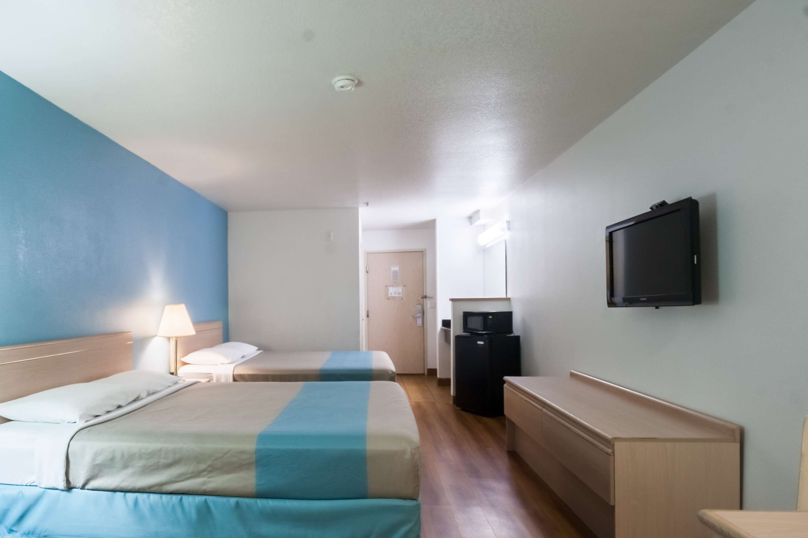 Ein Hotelzimmer mit zwei Betten, einem Schreibtisch, einem Fernseher und einer Mikrowelle.