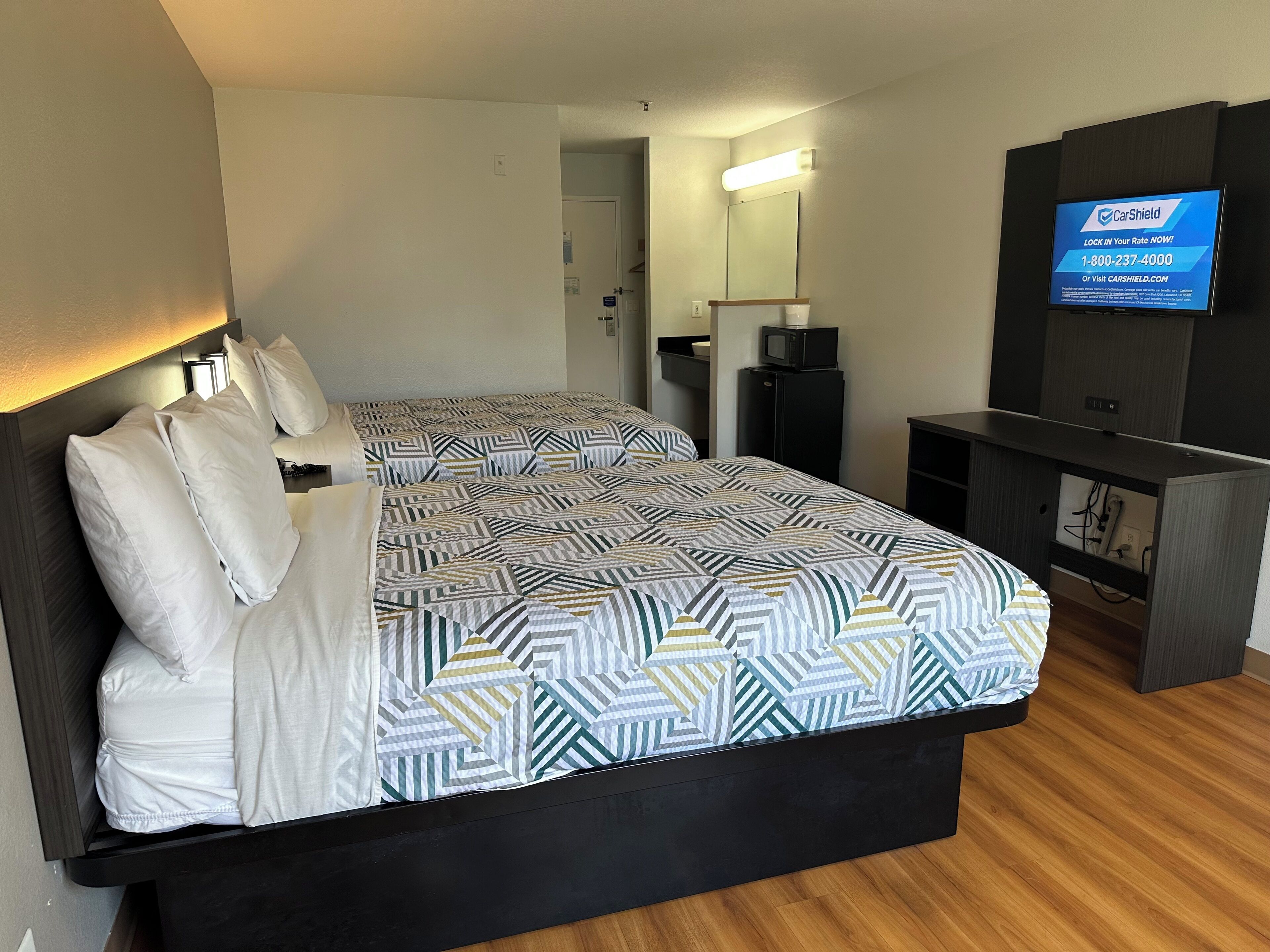 Une chambre d’hôtel avec un lit, un bureau, une télévision et un miroir.
