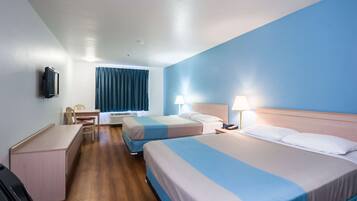 Une chambre d’hôtel avec deux lits, un bureau, une chaise, une télévision et une fenêtre avec des rideaux.