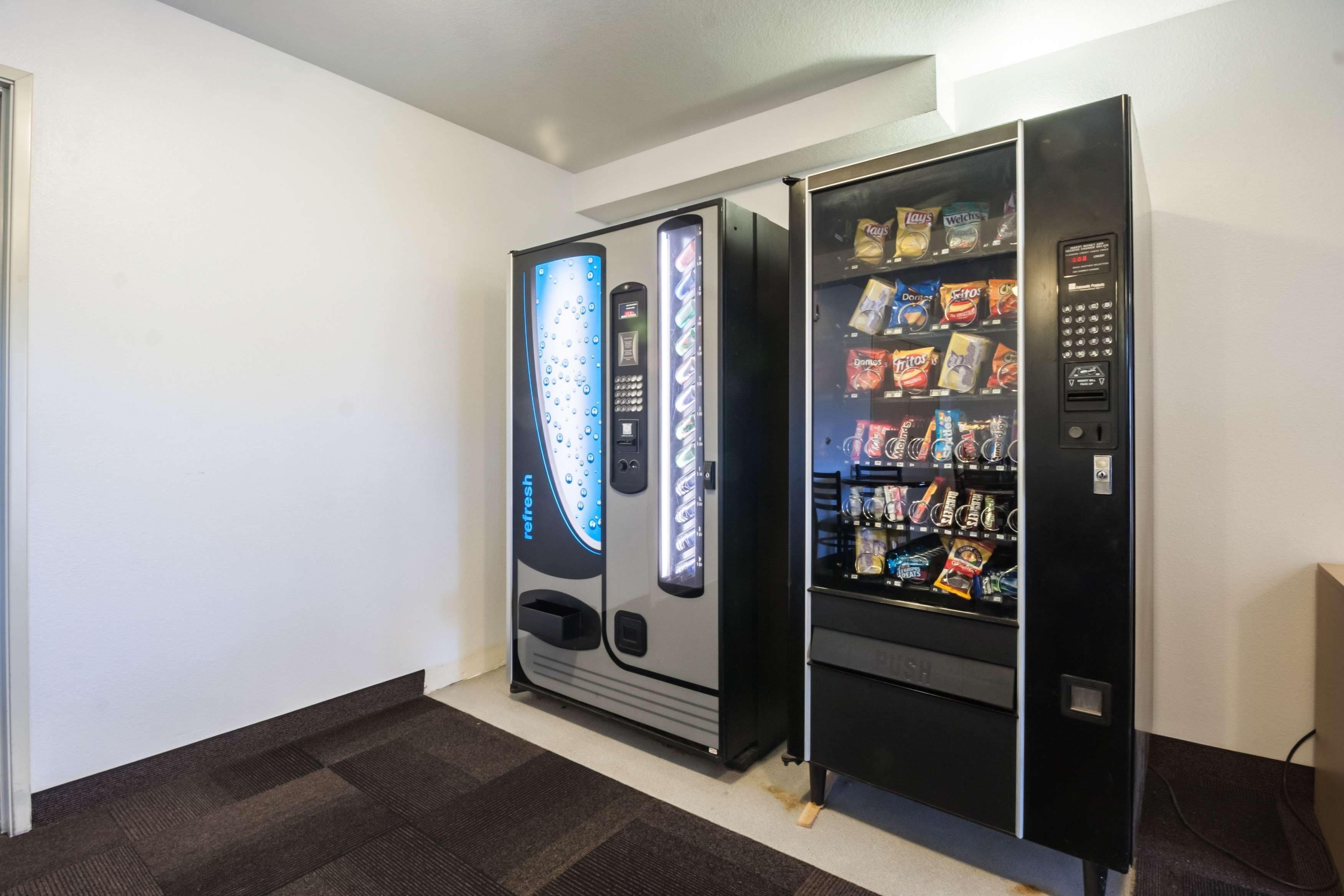 Two vending machines in a room with a carpeted floor and white walls.