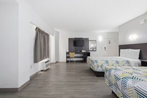 Habitación de hotel con dos camas, un escritorio, una silla, un televisor y una ventana con cortinas.