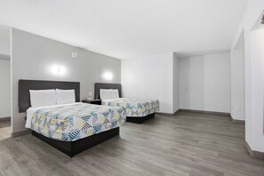 A hotel room with two beds, a wooden floor, and a white wall with a light fixture. - Motel 6 Washington, DC (Washington)