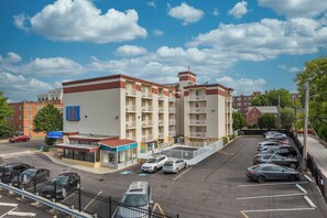 A multi-story hotel with a parking lot in front, featuring a 'Welcome' sign and a blue handicap parking symbol. - Motel 6 Washington, DC (Washington)
