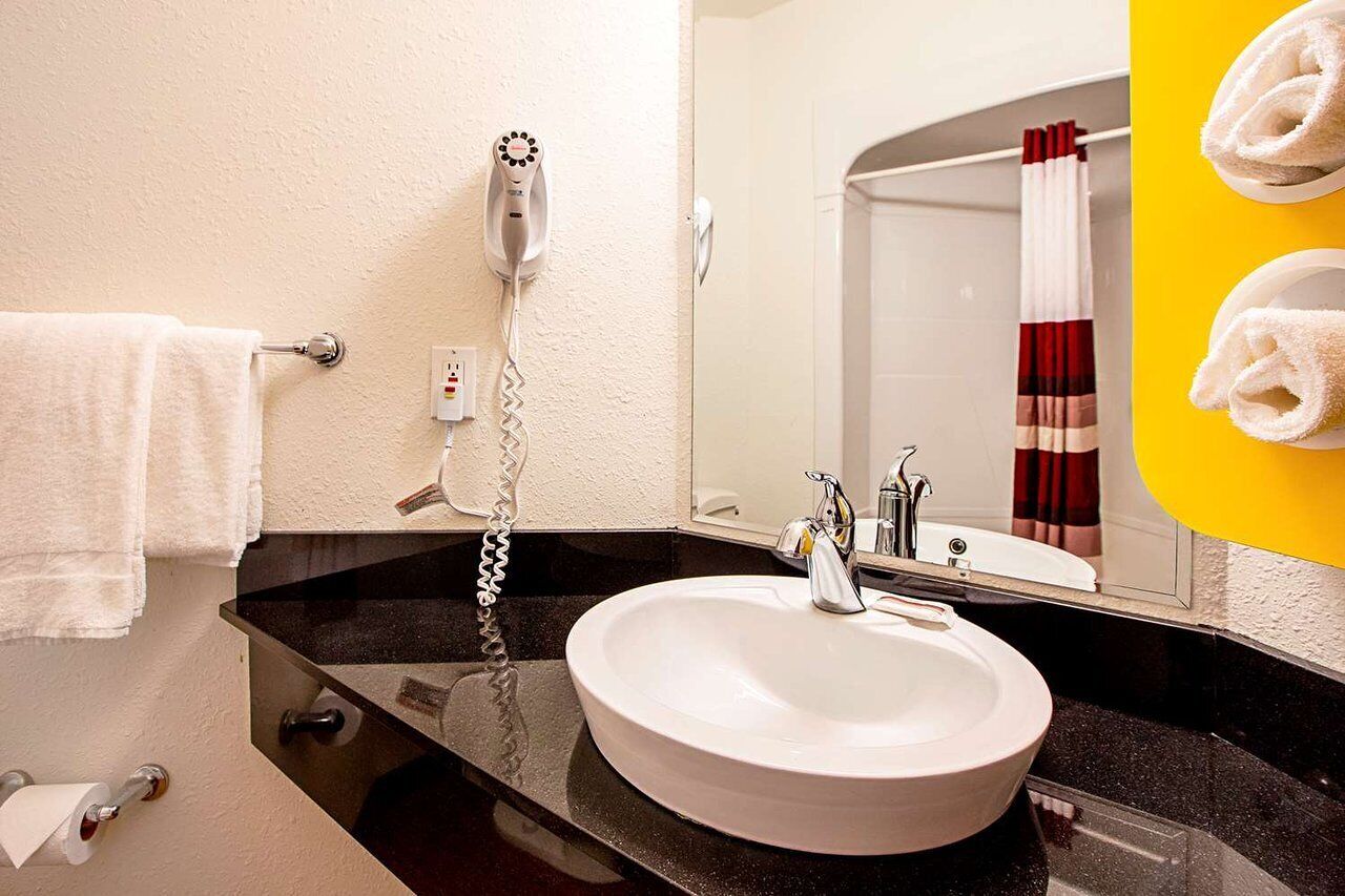 A bathroom with a white sink, a mirror, a towel rack, and a shower curtain.