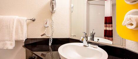 A bathroom with a white sink, a mirror, a towel rack, and a shower curtain.
