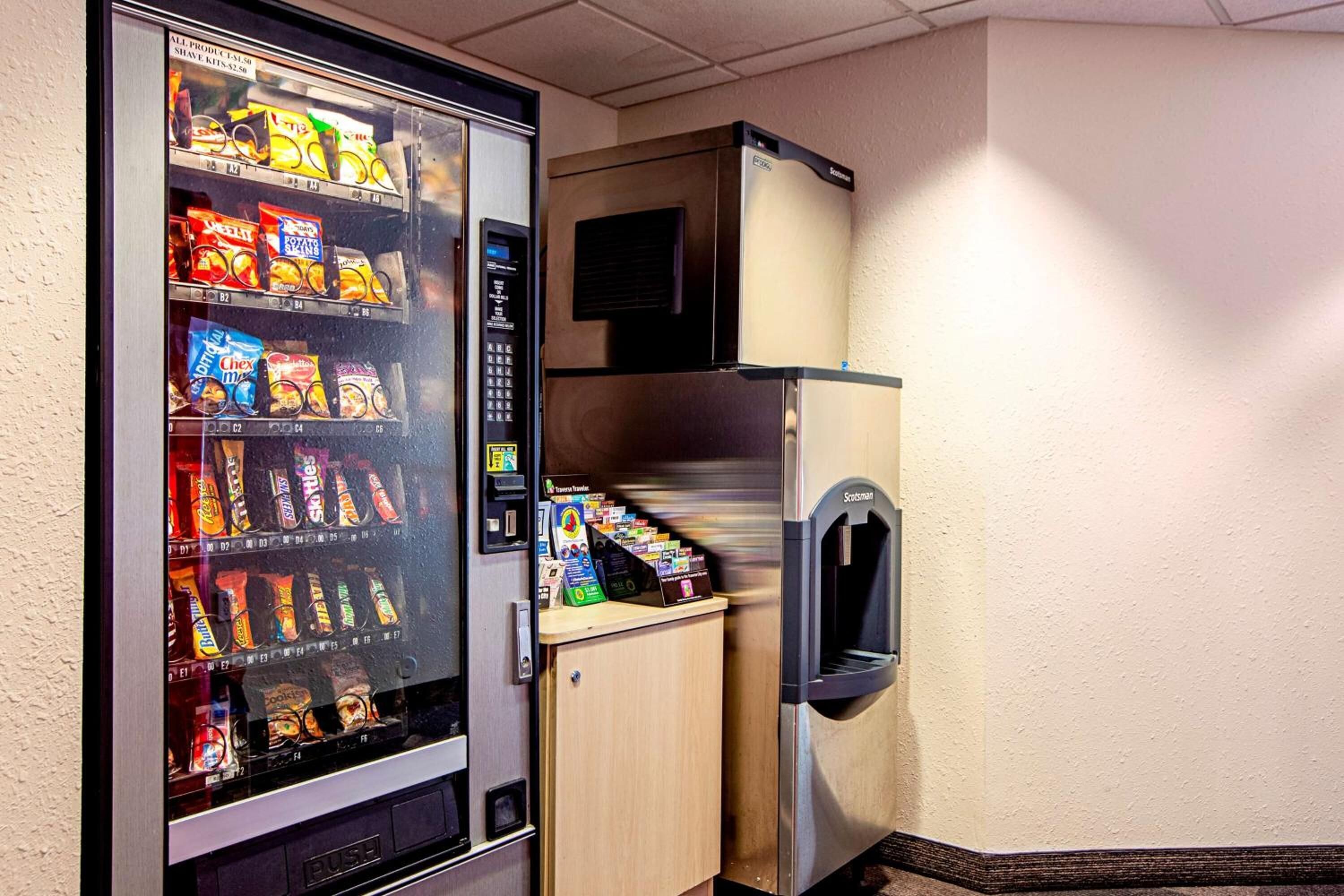 A vending machine stocked with snacks and a small refrigerator.
