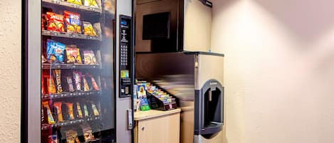 A vending machine stocked with snacks and a small refrigerator.