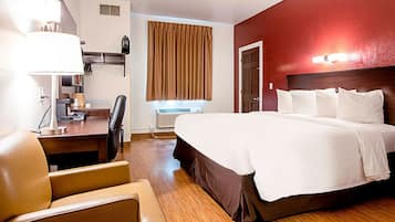 Habitación de hotel con una cama grande, un escritorio con lámpara, una silla, una ventana con cortinas y un calentador de pared.