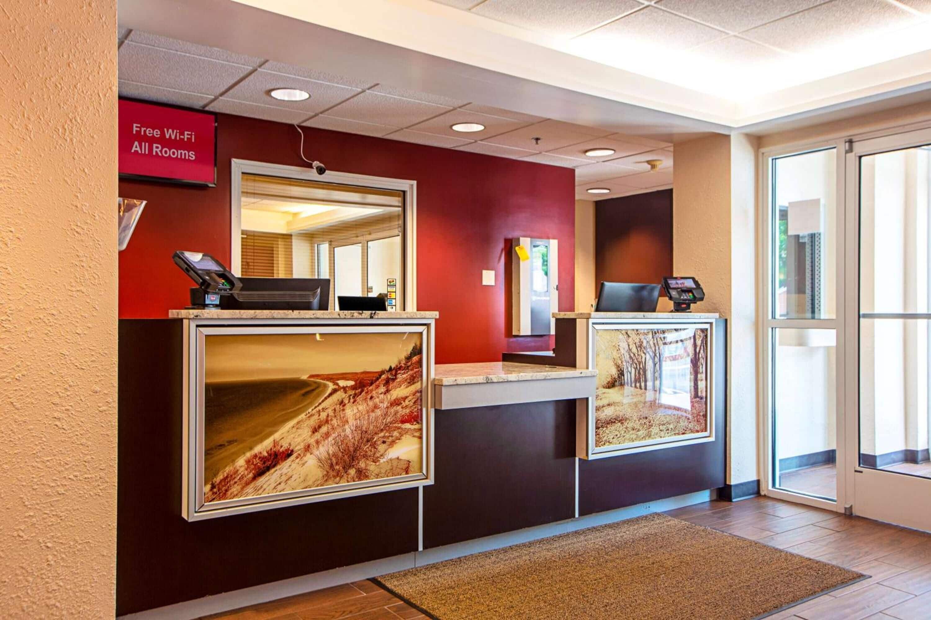 A reception desk with a red wall, a large window, and a sign indicating free Wi-Fi.