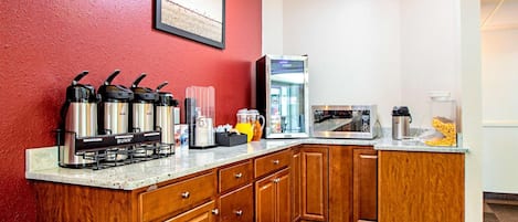 Una cocina compacta con armarios de madera, una estación de café, microondas y refrigerador.